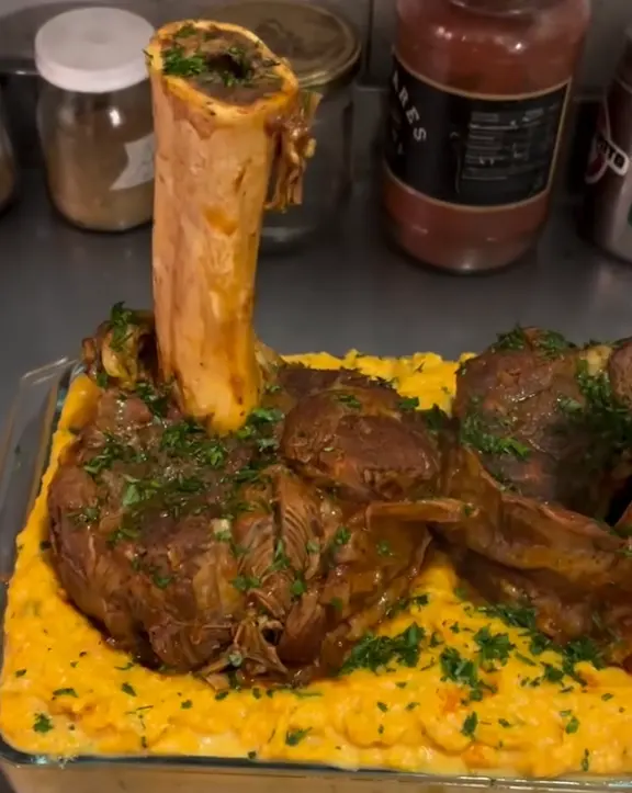 Ossobuco braseado con el hueso a la vista sobre un puré cremoso con perejil