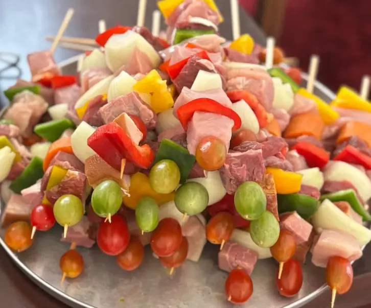Bandeja de pinchos con carne, cerdo, morrones de colores, cebolla y tomates cherry