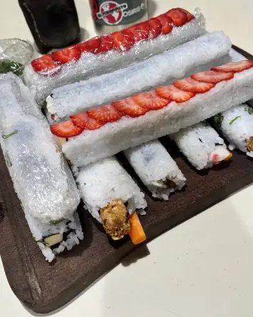 Rolls de sushi, algunos cubiertos con láminas de frutilla